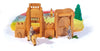 Handcrafted wooden castle playset with a surrounding wall, gate, and two knights on horses. One knight, the Ostheimer Red Knight - Riding, holds a lance, while the other carries a shield. There is a figure standing inside the castle and a colorful cloth forms the backdrop, resembling sky and ground. Perfect for imaginative play!