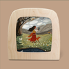 A mesmerizing silhouette scene from the Silhouette Only - Out of the Forest Silhouette for Toverlux Lamp showcases a woman in a red dress strolling with a fox across a grassy field. She is holding an open book and surrounded by magical silhouettes of trees and flowers below towering mountains under a cloudy sky, while in the distance, a sheep grazes peacefully.