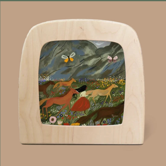 A small wooden frame displays the "Silhouette Only - Wild Spring" artwork, capturing a scene of a woman in a red dress running with horses across a flowery meadow. Butterflies dance against a mountain backdrop, crafting an enchanting and serene atmosphere.