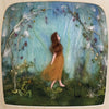 A felted artwork depicts a woman in a flowing dress walking through a whimsical forest. She strolls beneath an archway made of flowers and vines, illuminated by the Magic Silhouettes from the "Silhouette Only - Whispers of Spring" collection, set against a background of soft blues and greens.