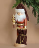 This limited-edition Christian Ulbricht Collectible Wooden Nutcracker - Natural and Gold Santa showcases a white-bearded Santa wearing a brown hat and holding a decorative golden tree. It is accompanied by a brown sack tied with a gold rope, while greenery elegantly drapes from the top right corner.