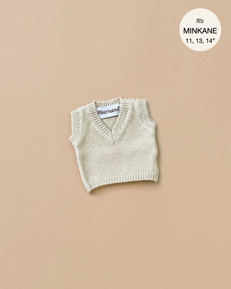 The Minikane Doll Clothing features a cream knit Leonardo tank top suitable for dolls, displayed against a light brown backdrop. It is designed to fit Minikane Babies sized 11, 13, and 14 inches.