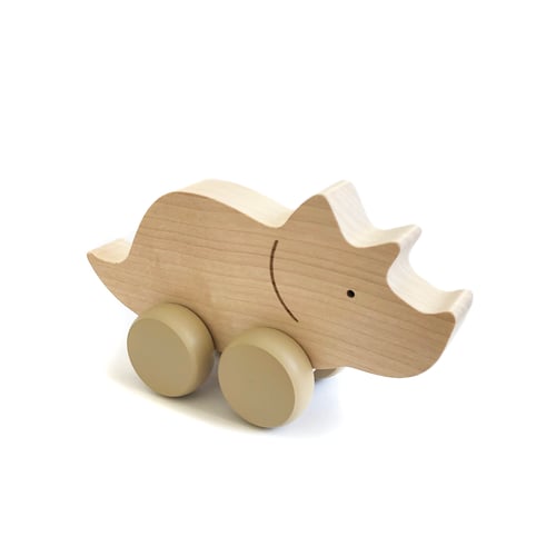 A Wooden Triceratops Dinosaur Push Toy, featuring a natural wood finish and a simple design with two light brown wheels. Handmade in Poland, it develops fine motor skills while providing endless fun for your little one.