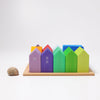 The Grimm's Houses, a set of vibrant hand-painted wooden blocks displayed in a tray, range in color from purple to green and are accompanied by a small snail on a white background.