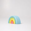 A minimalist, pastel-colored Grimm's Small Wooden Rainbow, Pastel resembling a Rainbow tunnel. Crafted from durable lime wood, the versatile toy consists of five arches in blue, green, yellow, pink, and orange, arranged from largest to smallest on a white background.