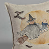 The Coral & Tusk Supermoon Spell Pillow showcases an illustration of a small figure in a flowing cape and pointy hat riding a broomstick, holding a Wizard Puppy with a scarf, set against the backdrop of a glowing yellow moon and flying bats.