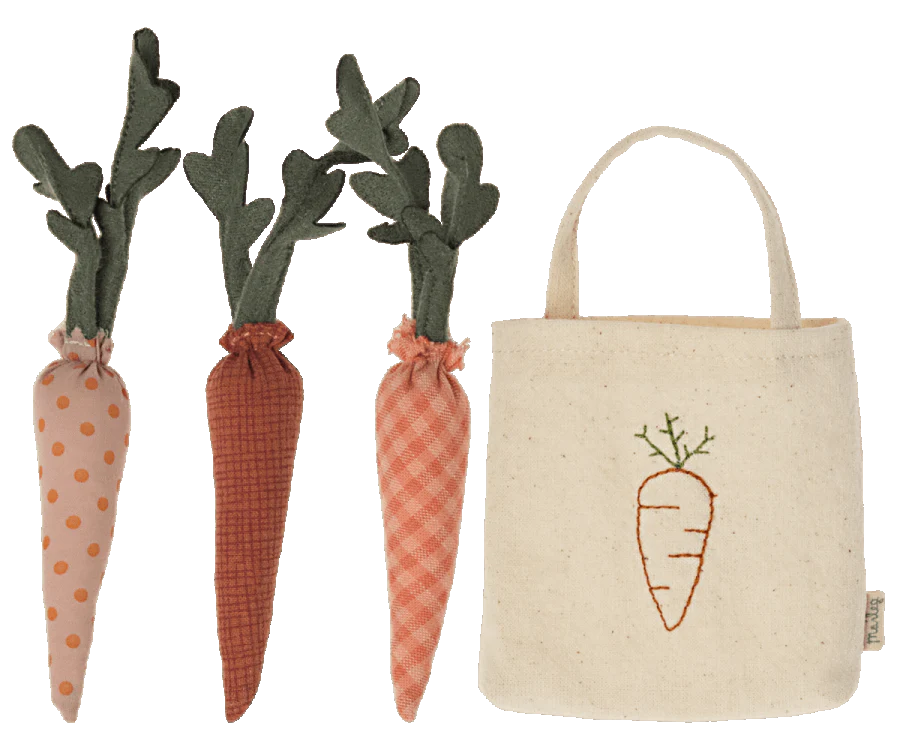 Three fabric carrots with different patterns (polka dots, gingham, and solid) next to a small beige tote bag with a carrot embroidery on the front. Perfect for imaginative play or for bunnies to enjoy, the Maileg Carrots In Bag have green fabric leaves and varying shades of orange.