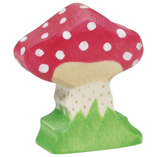 A handcrafted wooden toy mushroom with a red cap decorated with white spots. The stem, made from maple and beech wood, has a natural tone with green grass-like patterns at the base, creating a whimsical, nature-inspired look reminiscent of the charming Holztiger Toadstool figures.