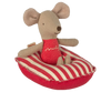 A small, brown fabric mouse with large ears is sitting on a Maileg Beach Raft, Small Mouse - Red stripe. The mouse, made of soft cotton fabric, is wearing a red outfit with yellow stitching. Its petite size makes it perfect for baby mice sizes or as a charming addition to a small boat’s decor.