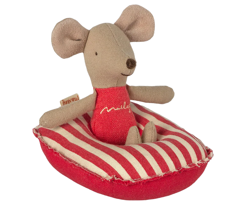 A small, brown fabric mouse with large ears is sitting on a Maileg Beach Raft, Small Mouse - Red stripe. The mouse, made of soft cotton fabric, is wearing a red outfit with yellow stitching. Its petite size makes it perfect for baby mice sizes or as a charming addition to a small boat’s decor.