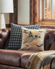 A cozy autumn-themed living room corner featuring a plush leather sofa adorned with a Supermoon Spell Pillow showcasing a witch and owl design, beside a window with a fall view. A plaid throw blanket adds warmth.