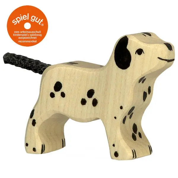 A small wooden toy dog with black spots and a black rope-like tail, designed in a simplistic style. Handcrafted from light-colored wood, the Holztiger Dalmatian Dog, Small features a round orange "spiel gut" award sticker in the upper left corner. This delightful piece is part of the renowned HOLZTIGER figures, proudly made in Europe.