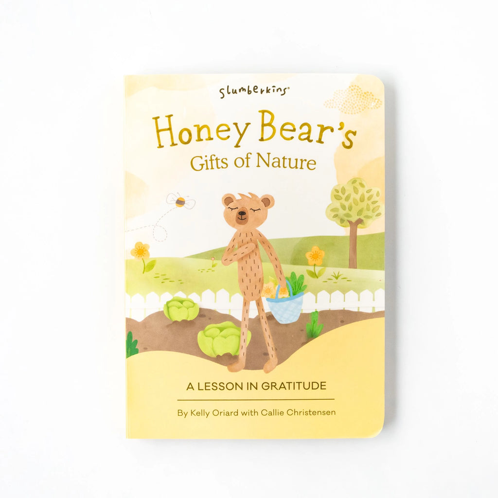 Cover of the children's book "Slumberkins A Lesson in Caring Board Book Set" by Kelly Oriard and Callie Christensen. It features an illustrated bear, embodying caring, holding a basket in a garden with bees, plants, and trees against a white picket fence. This charming book teaches social-emotional topics.