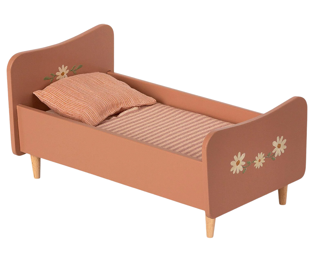 A small, Maileg Wooden Bed, Mini painted in a muted orange color featuring floral decorations and handpainted details of bunnies and rabbits on the headboard and footboard. The bed is furnished with a striped mattress and an orange pillow, supported by four short wooden legs.