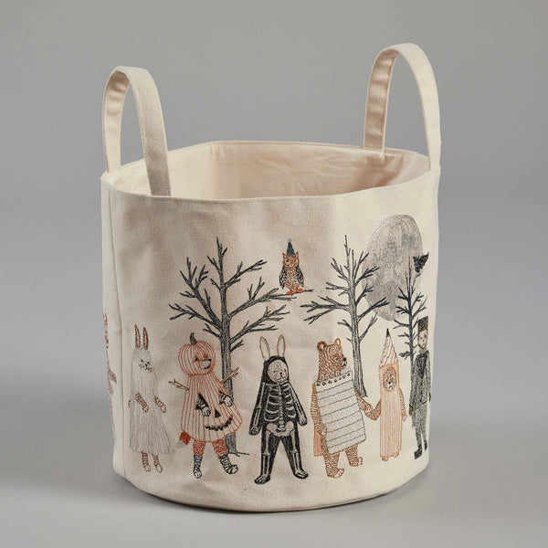 The Coral & Tusk Full Moon Masquerade Bucket, a fabric storage basket with two handles, features whimsical illustrations of animals in human clothing. Among them are a rabbit, a bear, a skeleton, and other characters parading under bare trees and the full moon in the background, evoking a charming Full Moon Masquerade.