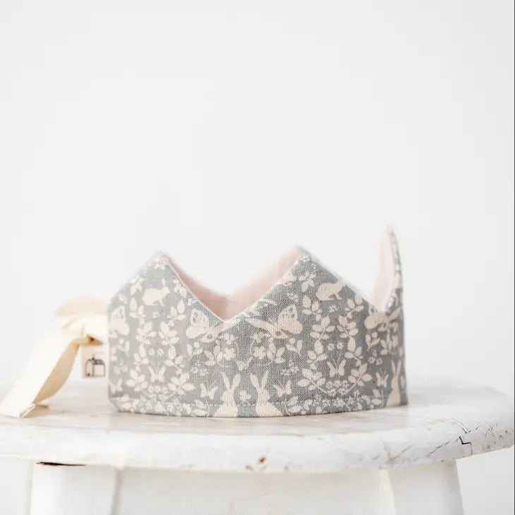 A Forest Reversible Birthday Crown featuring a delicate floral and rabbit print, displayed on a white surface against a soft white background.