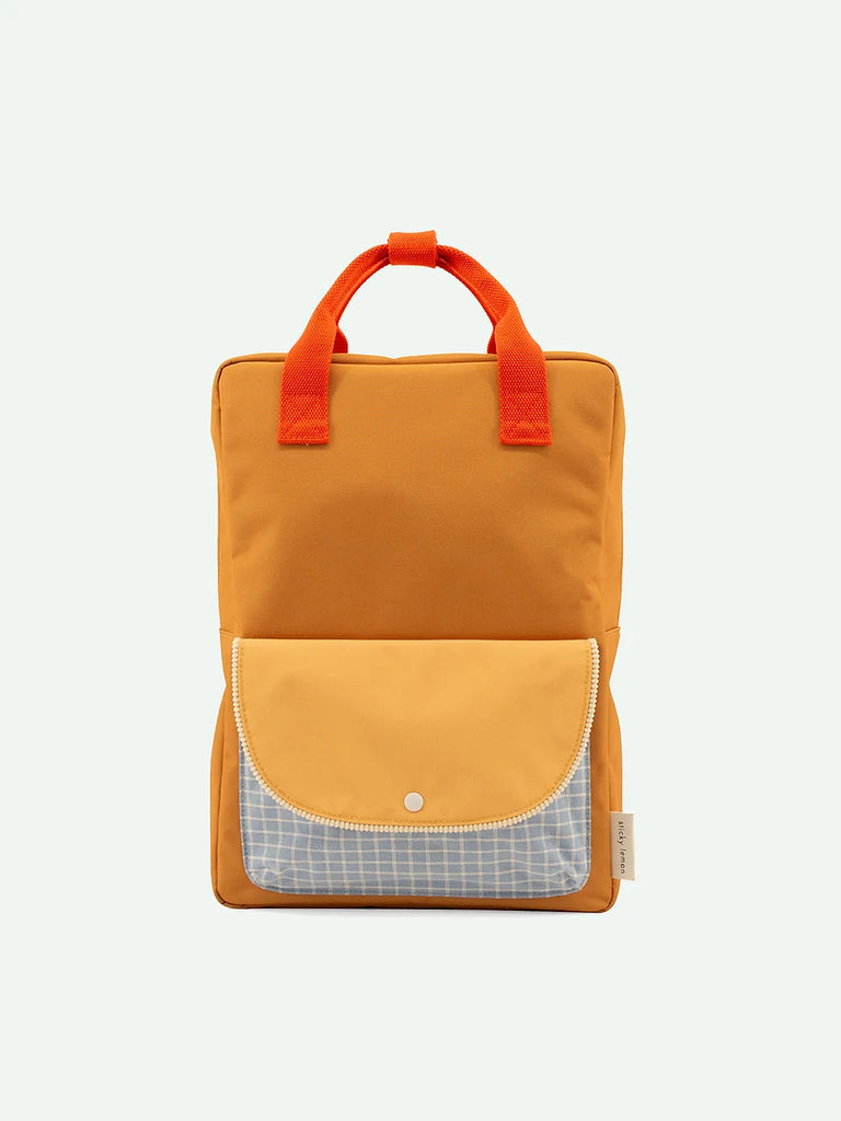 A rectangular orange Sticky Lemon Backpack Large | Farmhouse | Envelope | Homemade Honey crafted from waterproof nylon features two short orange handles. It has a front pocket with a flap; the main section of the pocket is light yellow and the flap is light gray with a white grid pattern secured by a snap button, embodying Sticky Lemon’s signature style.