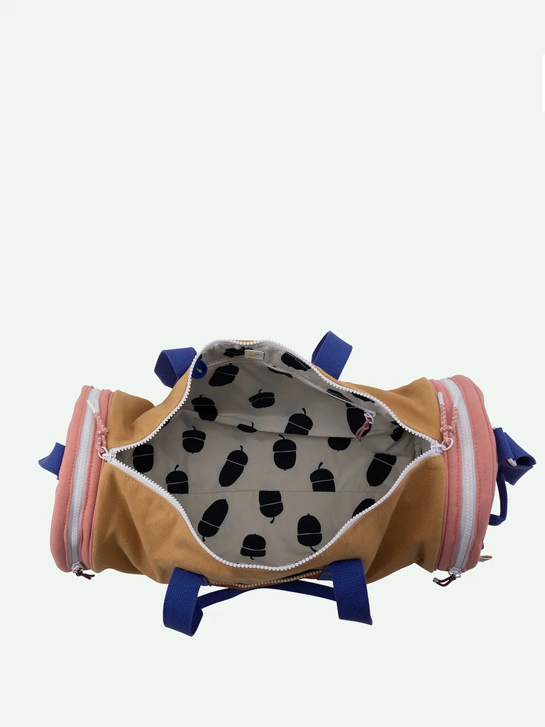 An open, empty Sticky Lemon Duffle Bag from the Adventure Collection, Cousin Clay edition, standing upright on a white background. The bag is beige with pink and blue accents, featuring a white interior decorated with a black polka dot pattern.