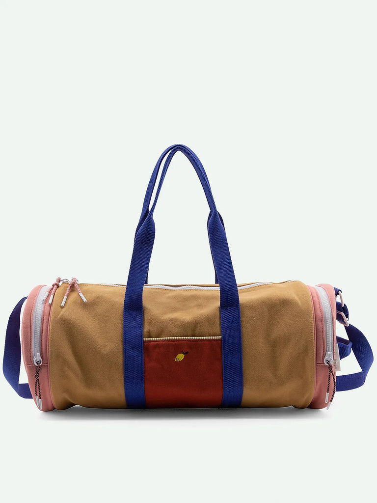 Sticky Lemon duffle bag in color blocks of blue, tan, and pink with blue handles, an adjustable shoulder handle, and a small logo patch, set against a plain white background.