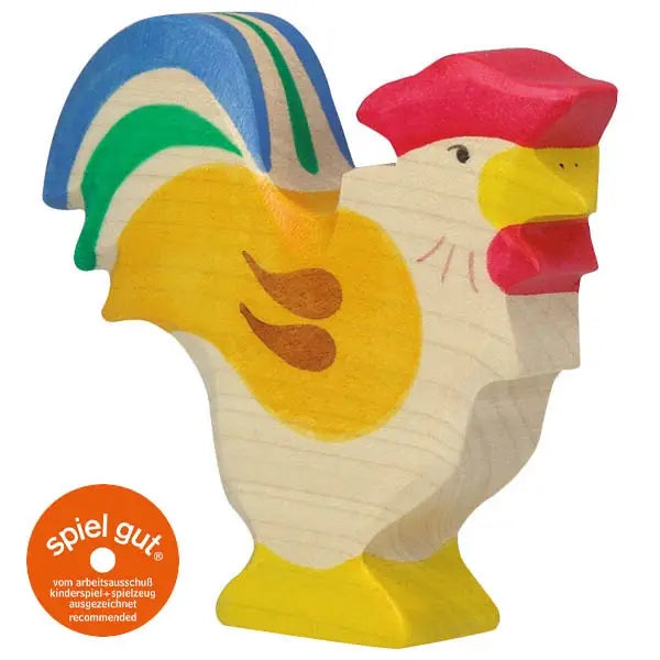 A colorful Holztiger Rooster with a yellow body, brown wing markings, blue and green tail feathers, and a red comb and beak. Handcrafted in Europe, it features an orange circular "spiel gut" recommendation seal on the bottom left.