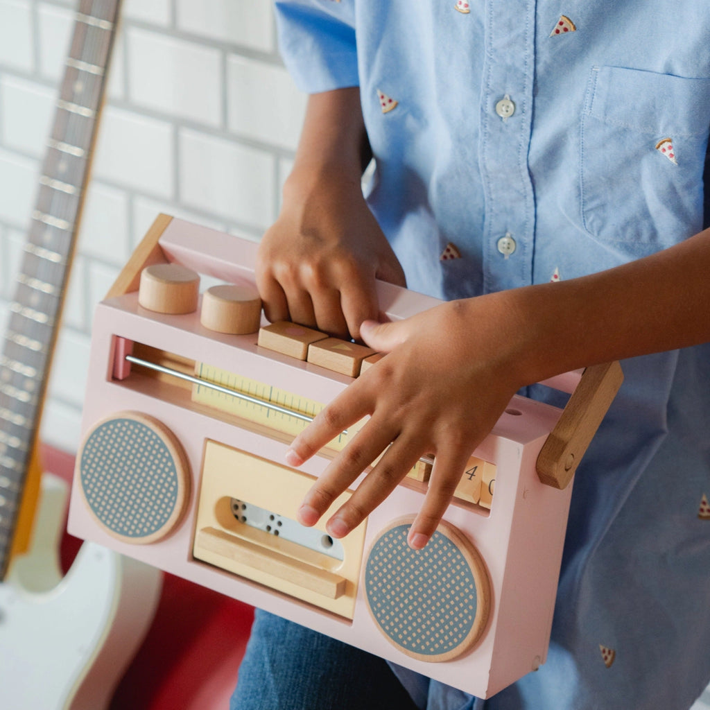 Child playing with a Retro Wooden Tape Recorder alongside an electric guitar in the background.