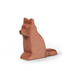 A small wooden dog figurine carved in a minimalist style is part of the Ostheimer collection. The Shepherd's Dog, crafted from sustainably sourced materials, sits upright with its tail curled around its right side. The natural brown wood has subtle grain textures visible, and the facial features are simple and minimal.