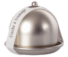 A small silver Maileg Cheese Bell with a metallic dome lid, featuring a white fabric ribbon around it. The ribbon has the French words "Cloche à fromage" printed on it, hinting at the delicious surprise inside for any cheese lover.