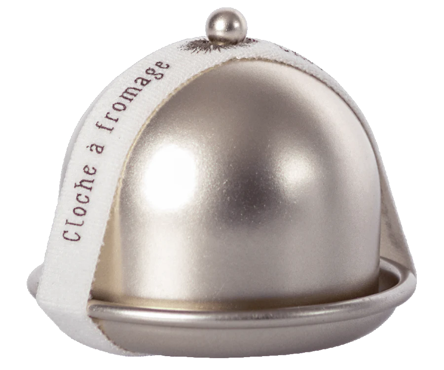 A small silver Maileg Cheese Bell with a metallic dome lid, featuring a white fabric ribbon around it. The ribbon has the French words "Cloche à fromage" printed on it, hinting at the delicious surprise inside for any cheese lover.