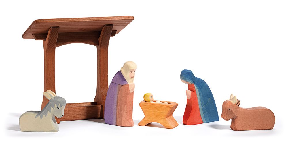 Ostheimer's Manger With Roof is a wooden nativity scene that includes a stable, Mary, Joseph, baby Jesus in a manger, along with a donkey and a cow. These handcrafted figures are simple yet colorful, perfect for imaginative play against a crisp white backdrop.