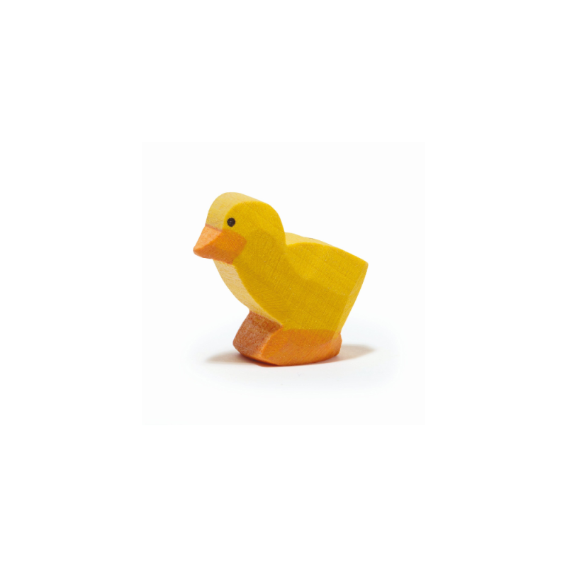 A small, yellow wooden Ostheimer Chick, Yellow stands on a white background. The chick, reminiscent of handcrafted wooden toys by Ostheimer, has an orange beak and feet and simple black dot eyes, giving it a cute and minimalist appearance perfect for imaginative play.