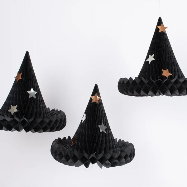 Three Meri Meri Honeycomb Witch Hat Decorations are hanging against a white background. Each black, conical Halloween decoration is adorned with shiny metallic stars in gold and silver.