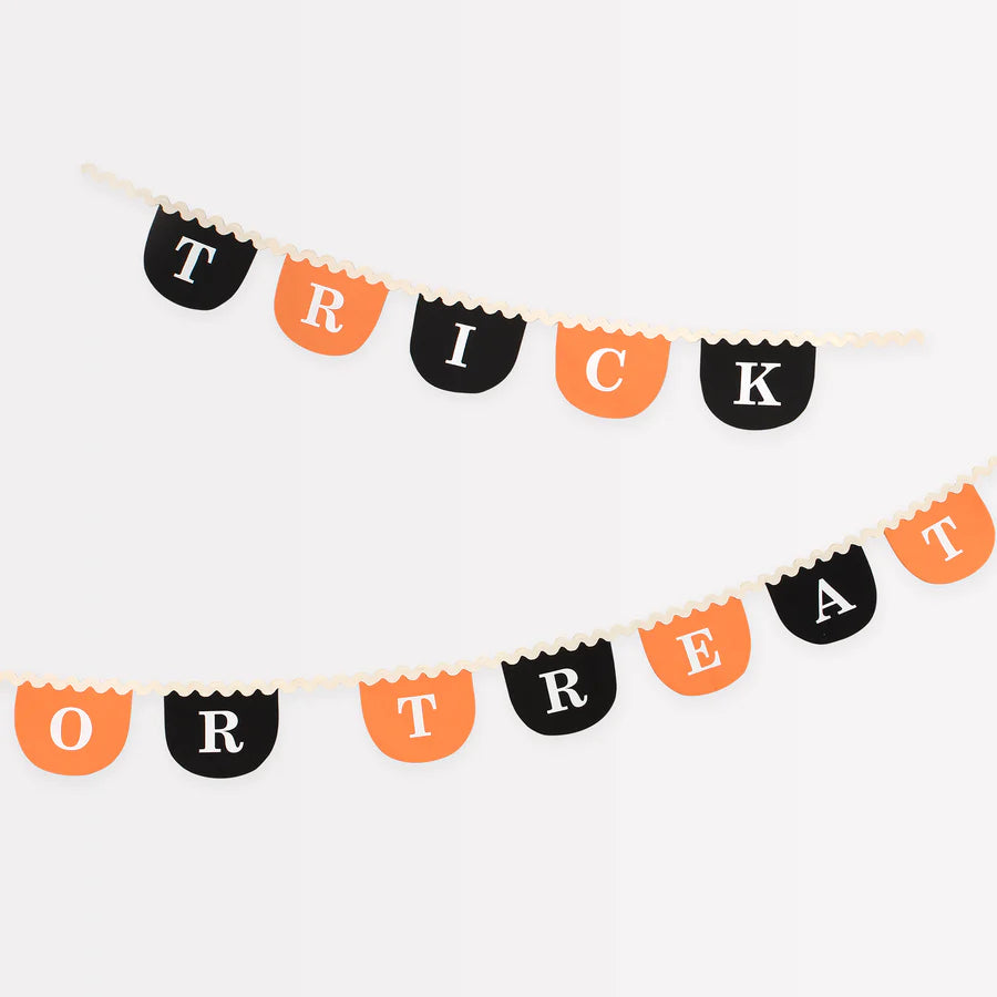 The Meri Meri Trick Or Treat Fabric Garland set, featuring two reusable Halloween-themed fabric garlands with scalloped edges, hangs against a white background. The top garland spells out "TRICK," while the bottom one spells out "OR TREAT," with letters alternating between black and orange backgrounds. This festive decoration adds a perfect touch to any spooky celebration.