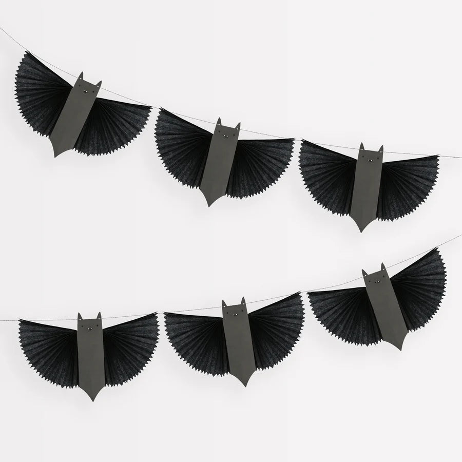 The Meri Meri Bat Garland - Final Sale features a set of black bat-shaped paper bats strung together on two parallel lines against a white background. The bats have pointed ears and outstretched wings, making it a festive and spooky garland perfect for your Halloween decoration needs.