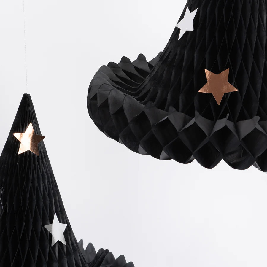 Close-up of Meri Meri Honeycomb Witch Hat Decorations - Final Sale featuring black, honeycomb-patterned paper in the shape of conical witch hats, adorned with metallic gold and silver star cutouts. The white background creates a striking contrast with these Halloween decorations.