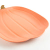 A close-up of the Meri Meri Reusable Bamboo Pumpkin Plate, shaped like a pumpkin with a small brown stem detail at the top left corner. The durable plate features subtle grooves mimicking the ridges of a real pumpkin and is set against a plain white background.