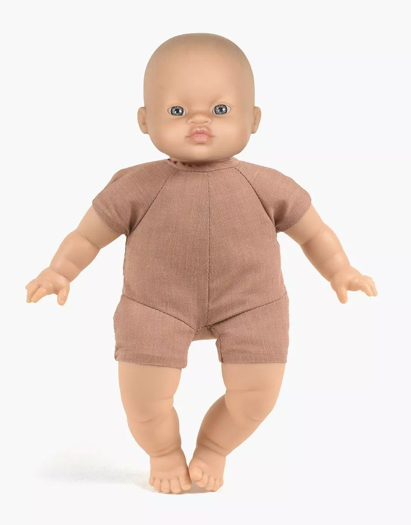 A Minikane Soft Body Doll (11") - Maé, dressed in a simple brown one-piece outfit, stands upright against a plain white background. Made from phthalate-free vinyl, this doll’s neutral facial expression and slightly outstretched arms invite imaginative playtime.