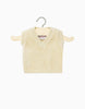 A cream knit Leonardo tank top, designed for Minikane babies and dolls, is showcased on a wooden hanger against a simple white background.