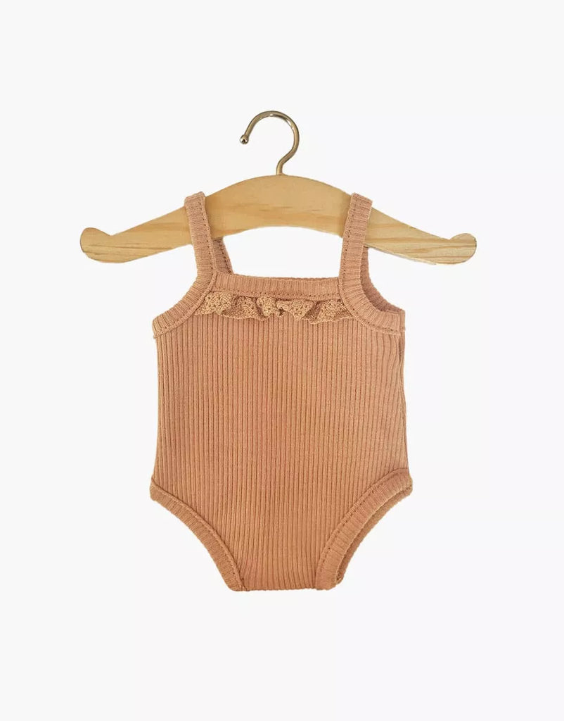 The Minikane Doll Clothing, Les P'tits Basique Jumpsuit in a brown sugar ribbed knit, features shoulder straps and decorative lace trim on the chest, making it an ideal fit for Minikane Gordis dolls. It is displayed on a wooden hanger against a plain white background.