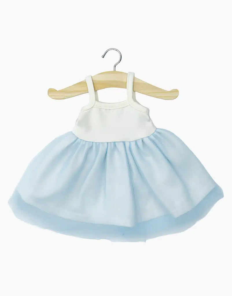 The Rosella Tutu in Sky Blue, a charming child's dress designed in France, hangs on a wooden hanger. The dress showcases a sleeveless white bodice paired with a light blue, fluffy tulle skirt. Hand washable and ideal for Minikane dolls, it stands out beautifully against the plain white background.