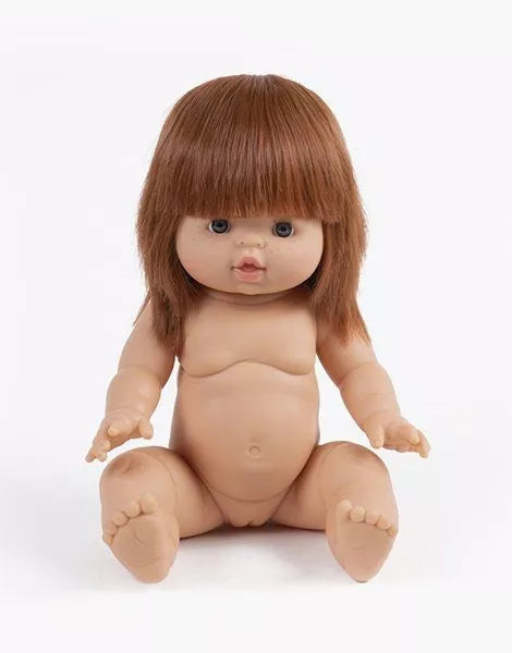 A lifelike Minikane Baby Doll (13") - Capucine with brown hair, blue eyes, and a neutral expression sits upright with its legs spread and arms extended forward. The anatomically correct doll is unclothed, showcasing detailed features like fingers, toes, and a belly button.