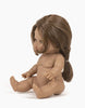 Leopoldine, the anatomically correct Minikane Baby Doll (13"), with brown skin and long brown hair styled in a ponytail, sits upright against a plain white background. The unclothed doll has its arms and legs slightly bent and emits a delicate natural vanilla scent.