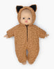 A Minikane Babies Doll cuddles up in a Brown Sugar Sherpa Costume, complete with adorable bear-like ears on the hood. The textured fabric, akin to fur, sets a cozy ambiance as the doll rests against a pristine white background.