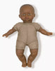 The Minikane Soft Body Doll (11") - Ondine, featuring dark skin and short hair, is dressed in a simple beige onesie. Crafted from phthalate-free vinyl, this doll has a neutral facial expression and is positioned upright against a plain white background, making it an ideal bedtime companion.