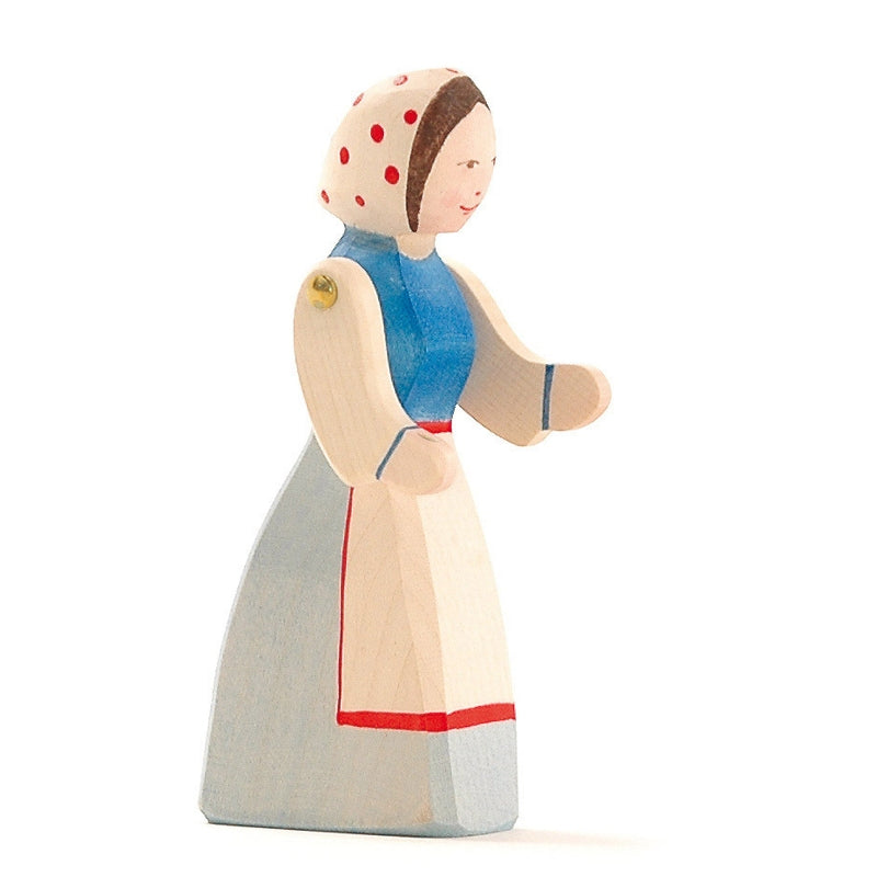 An Ostheimer Farm Wife. She wears a white headscarf with red polka dots, a blue top, and a long white apron with red trim over a light blue skirt. The figure, reminiscent of Ostheimer toys, is hand-painted with simple, charming details perfect for imaginative play.