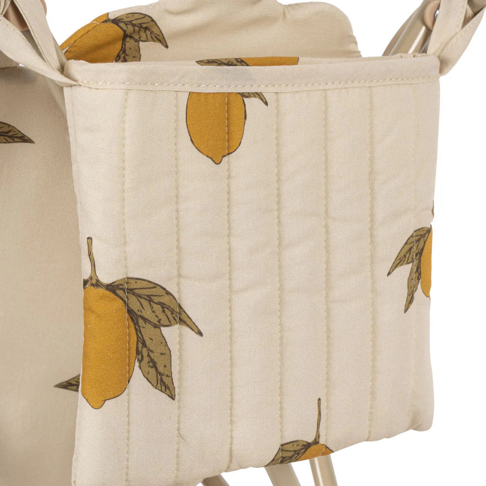 A quilted, cream-colored fabric featuring a lemon and green leaf pattern from the Konges Sloejd Doll Stroller - Grand Lemon, ideal for removable stroller covers or adding charm to a doll stroller.