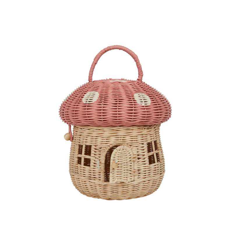 A handwoven Olli Ella Mushroom Basket purse with a pink domed lid, resembling a mushroom. It features a structured handle and a small front door design, set against a plain background.