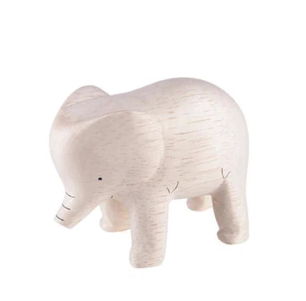 A small, light-colored Handmade Tiny Wooden Safari Animals - Elephant with simple, minimalist features stands on a white background. The handcrafted wooden animal has a smooth texture and faint lines etched to represent details. Its trunk is slightly lifted, and it has a small painted eye.