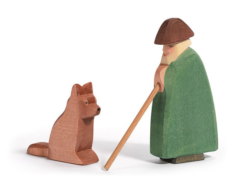 An Ostheimer Shepherd With Staff stands holding a walking stick, facing a handcrafted wooden toy figure of a sitting red fox. Both figures, made from sustainable materials, are positioned against a white background.