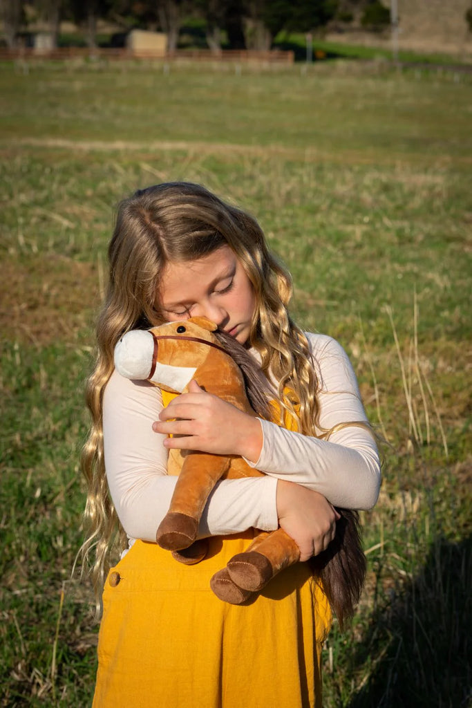 A girl hugging a soft and snuggly Stormy the Horse Stuffed Animal, perfect for babies.