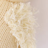 Close-up view of a Cuddle + Kind Baby Duckling hand-knit fabric with frayed edges and visible fluffy threads, highlighting its texture.